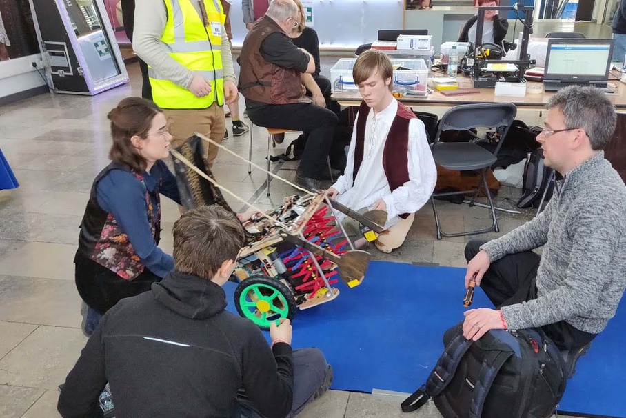 Students and a teacher sitting around their robot